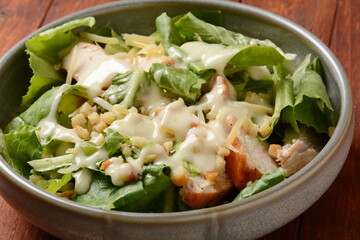 Caesar Salad with grilled chicken, Cheese and Croutons with lettuce, on plate.  Grilled chicken breasts and fresh vegetables in plate.