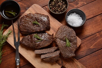 Grilled juicy beef steak with rosemary, fried meat, close-up. Top Blade steaks on wooden board
