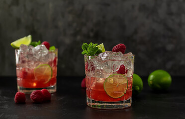 Bourbon or rum raspberry smash cocktail with lime and mint. Refreshing cold drink. dark background,...