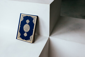 The Qur'an is the holy book in Islam on a white shelf