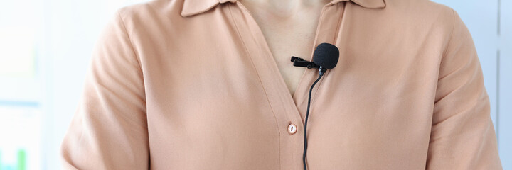 Small black microphone attaching to woman shirt closeup