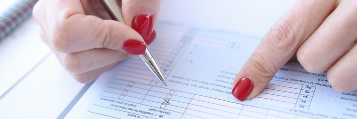 Woman with red manicure filling out questionnaire closeup