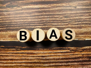Word BIAS with block cylinder on a wooden background.