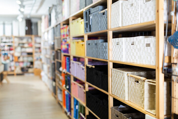 Variety of decorative storage boxes displayed on shelving in household goods store. Concept of goods to organize home space