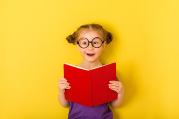 baby girl is holding book textbook and surprised.