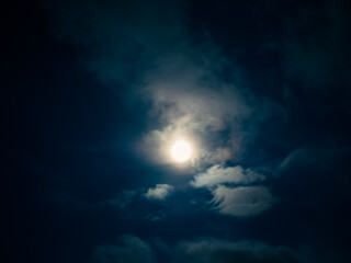 Fototapeta na wymiar Full moon among clouds in the night sky.