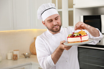 Happy professional confectioner decorating delicious cake in kitchen