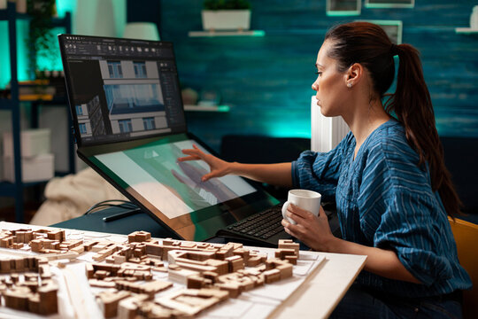 Architectural designer doing engineering sketch using touchpad screen technology monitor computer at design workplace. Caucasian woman working on building plan for renovation project