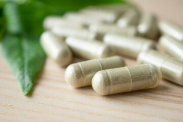 Herbal medicine capsules with Andrographis paniculata leaf on wood table