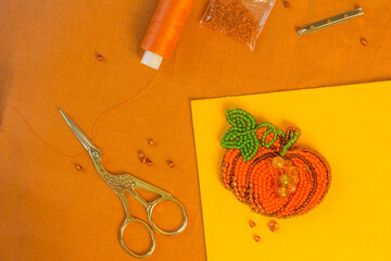 DIY present for halloween and thanksgiving day. Handmade beaded pumpkin. Jewelry designer making brooch with beads