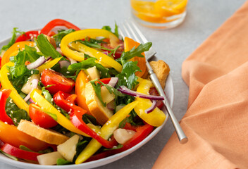 Light summer fresh salad with colorful tomatoes and croutons, sweet peppers and pineapple with sesame seeds, water with kumquats