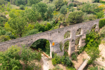 Fototapeta na wymiar Scenic view from drone of medieval arched aqueduct in Sant Pere de Riudebitlles village in Spain on summer day