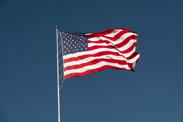 Flag of the USA is waving on blue sky background. National symbol of the United States of America, independence, patriotism, freedom, honor, democracy concept