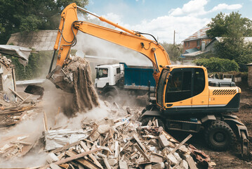 Excavator loads construction waste into truck for removal. Demolition of house. Building...