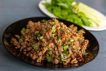 Spicy duck minced salad on wood table with fresh vegetables. Thai local food recipe Larb Ped delicious menu.