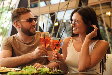 Lovely couple with Aperol spritz cocktails resting together at restaurant