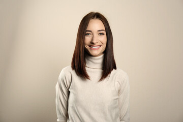 Fototapeta premium Portrait of pretty young woman with gorgeous chestnut hair and charming smile on light background