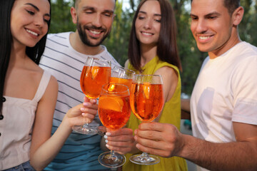 Friends clinking glasses of Aperol spritz cocktails outdoors