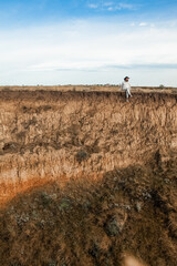 a man with a beard sits on the edge of a cliff with his legs dangling down in summer