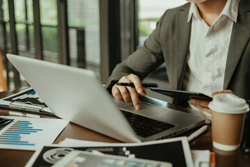 Business man working at office with tablet and laptop and documents on his desk, financial adviser analyzing data.