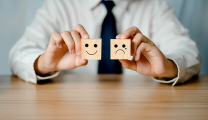 Business man holding a wooden cube Happy and angry icons compare service feedback and satisfaction...
