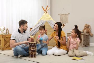 Happy family playing together near toy wigwam at home © New Africa
