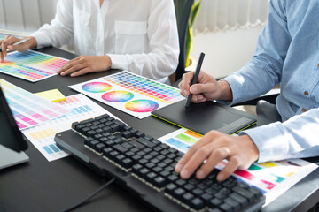 Graphic designer or creative working together coloring using graphics tablet and a stylus at desk...