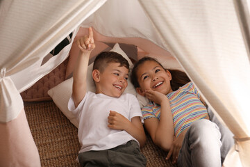 Cute little children lying in toy wigwam at home © New Africa