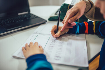 Little boy writes musical notes and violin key at home.