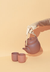 Hand holding Clay teapot minimal still life concept. Winter warm holiday time wallpaper