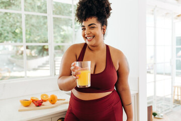 Smiling fitness woman holding juice at home