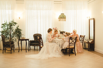Females sit at table and talk. Four person different age. Young adult, senior, mid age woman and child in vintage room indoors. Togetherness family good relationships generations. Happy female party