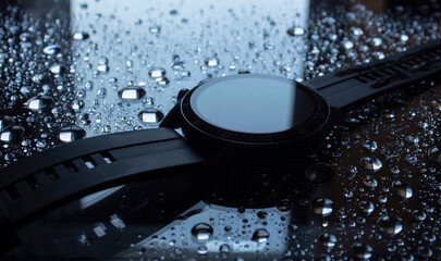 black watch lies on glass in drops of water