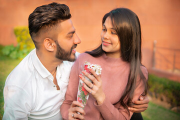Beautiful happy, romantic young couple sitting together with ram around and looking face to face with a toothy smile.