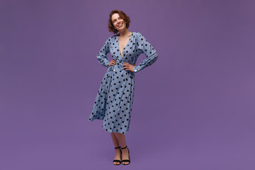 Full-length photo of young lady at studio. Pretty girl with short ginger hair, blue polka dot dress...