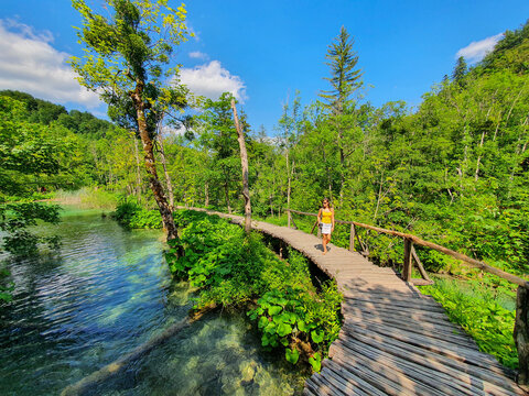 Female photographer explores scenic Plitvice Lakes national park on sunny day