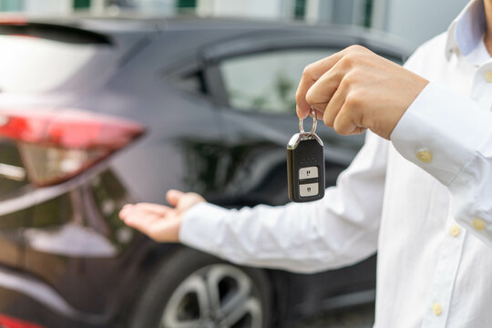 selling car, car sale, deal concept The dealer gives the car keys to the new owner or renter with an insurance contract.