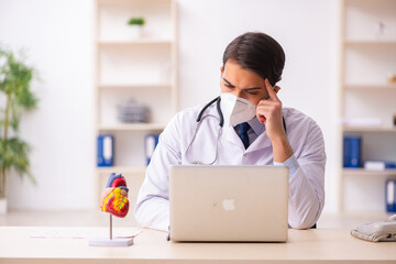 Young male doctor cardiologist working in the clinic during pand