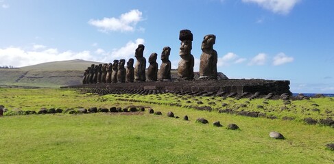 13 moai in Ahu Tongariki, Easter Island. Giant monoliths enclosed between a green lawn and the blue...