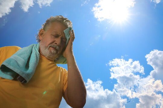 Senior man with towel suffering from heat stroke outdoors, low angle view. Space for text