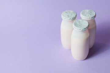 Bottles with probiotics and prebiotics dairy drink on light purple background.