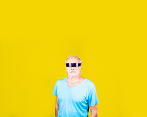 Elderly caucasian man wearing smart sci-fi glasses on yellow background with advertising copyspace
