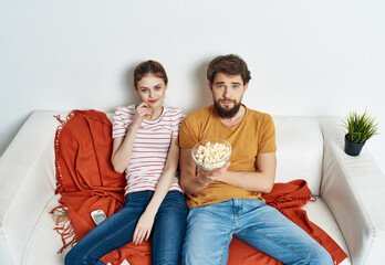 Obraz premium young couple with popcorn sitting on the couch watching movie entertainment