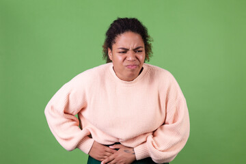 Beautiful african american woman on green background sad unhappy suffering from stomach pain