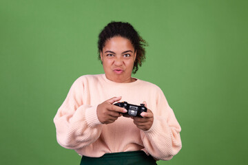 Beautiful african american woman on green background focused playing video games