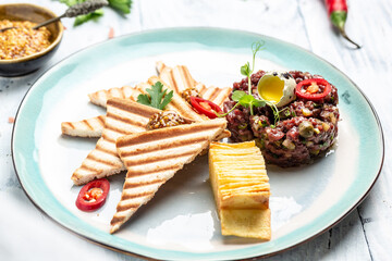 Steak tartare made from raw minced horse meat tartare with quail egg yolk. French cuisine. Delicious breakfast or snack