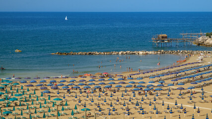 Panoramic view of Sant'Antonio beach full of umbrellas with its peculiar fishing trebuchet on the background , Termoli , Molise , Italy