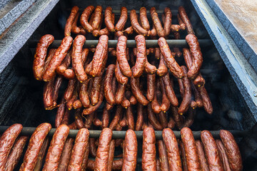 Close-up of smoked sausages from pork and beef meat hanging inside a wooden smokehouse....