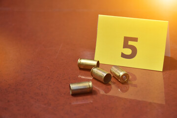 Pistol's bullet shells and yellow number paper sign on floor, concept for keeping evidence of the...