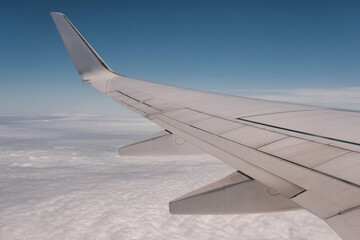 View of an airplane wing above the clouds on a sunny day.